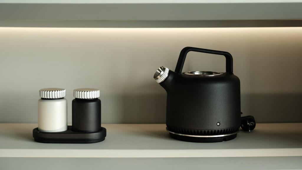 A kettle and shakers sit on a shelf.